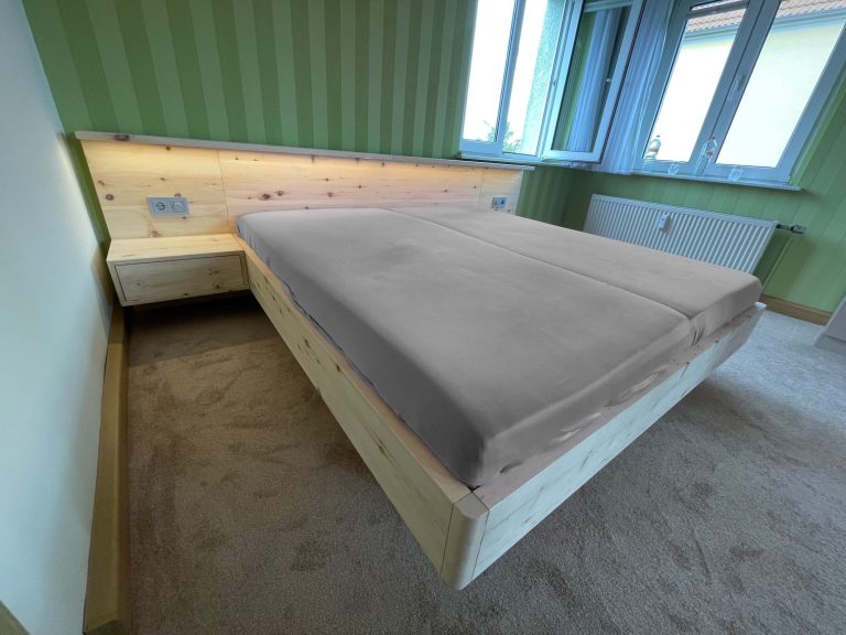 Zirbenbett Ein modernes Schlafzimmer mit einem Holzbett aus Zirpe und zwei seitlichen Nachttischen.