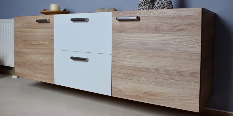 Moderner, niedriger Holzschrank mit zwei weißen Schubladen und zwei Holzpaneelen.