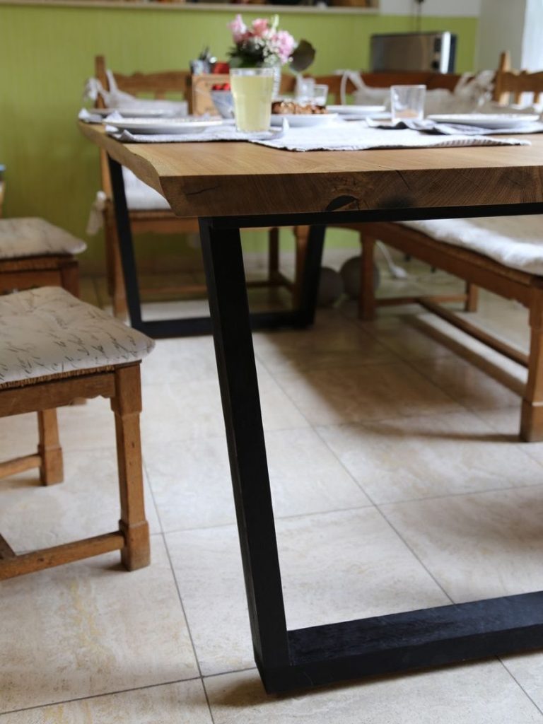 Esstisch aus Eiche - gefertigt in unserer Tischlerei in Wurzen Holztisch mit schwarzem Holzgestell in einem gemütlichen Essbereich.