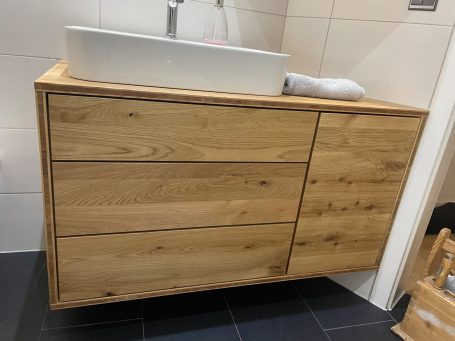 Holzwaschtisch mit weißem Becken und drei Schubladen, modern und schlicht gestaltet.