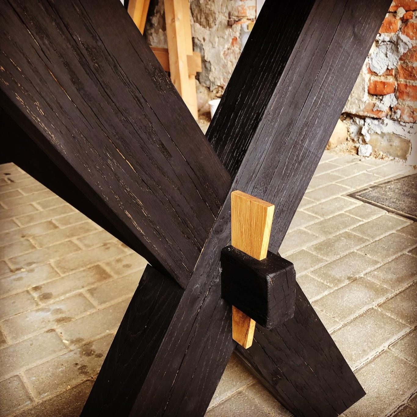 Andreaskreuz aus karbonisierter Eiche Dunkles Holzgestell mit einer Verbindung aus hellem Holz und schwarzem Element.