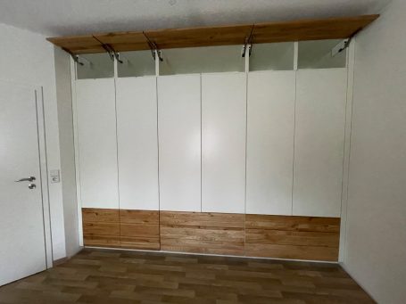 Schrank mit weißen Türen und Holzablage, moderne und minimalistische Gestaltung.