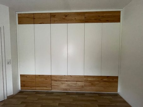 Moderne wandmontierte Schränke in Weiß und Holzoptik mit glatten Türen.